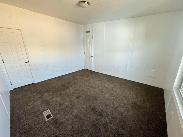 carpeted spare room with a decorative wall, a textured ceiling, and visible vents