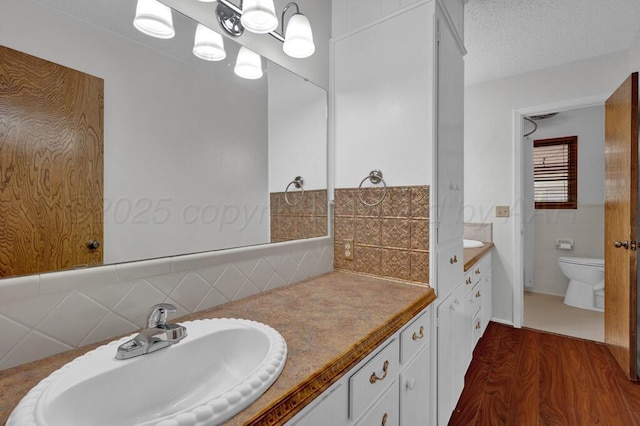 145 N Kingwood St, Hereford, TX 79045 - full bath featuring toilet, tasteful backsplash, wood finished floors, and vanity