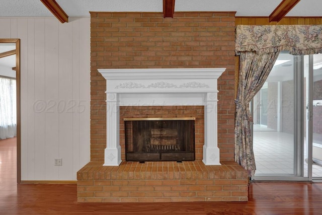 145 N Kingwood St, Hereford, TX 79045 - room details featuring wooden walls, a fireplace, a textured ceiling, wood finished floors, and beamed ceiling