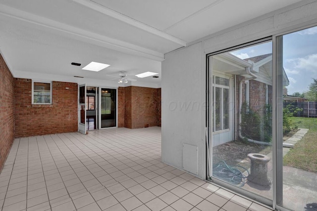 145 N Kingwood St, Hereford, TX 79045 - empty room featuring brick wall, a skylight, and tile patterned flooring