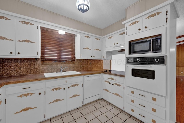 145 N Kingwood St, Hereford, TX 79045 - kitchen featuring light tile patterned flooring, white appliances, under cabinet range hood, tasteful backsplash, and a sink