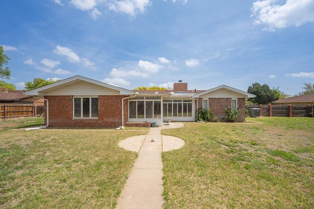 145 N Kingwood St, Hereford, TX 79045 - back of house featuring a fenced backyard, a lawn, a sunroom, and brick siding