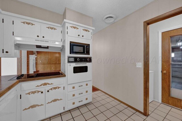 145 N Kingwood St, Hereford, TX 79045 - kitchen featuring dark countertops, built in microwave, black electric cooktop, under cabinet range hood, and oven