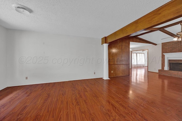 145 N Kingwood St, Hereford, TX 79045 - unfurnished living room with a brick fireplace, a textured ceiling, ceiling fan, and wood finished floors