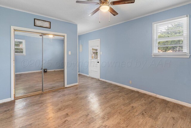 2209 N Beech Ln, Pampa, TX 79065 - unfurnished bedroom featuring crown molding, wood finished floors, a textured ceiling, baseboards, and a closet