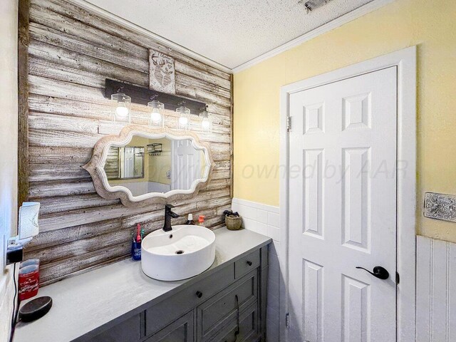 2209 N Beech Ln, Pampa, TX 79065 - bathroom featuring ornamental molding, vanity, wainscoting, and a textured ceiling