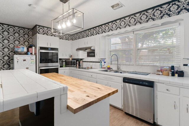 2209 N Beech Ln, Pampa, TX 79065 - kitchen featuring wallpapered walls, stainless steel appliances, a sink, under cabinet range hood, and white cabinets