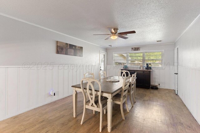 2209 N Beech Ln, Pampa, TX 79065 - dining room with light wood-type flooring, a textured ceiling, ceiling fan, a wainscoted wall, and a decorative wall