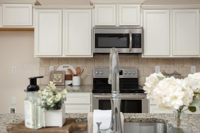 7308 Sinclair St, Amarillo, TX 79119 - kitchen with appliances with stainless steel finishes, tasteful backsplash, and light stone countertops
