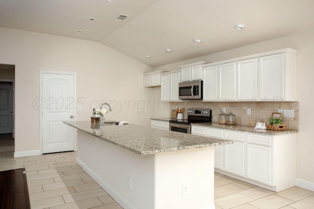 7308 Sinclair St, Amarillo, TX 79119 - kitchen featuring stainless steel appliances, lofted ceiling, tasteful backsplash, an island with sink, and white cabinetry