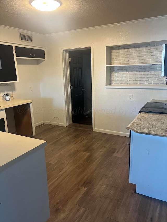 605 Star St, Hereford, TX 79045 - kitchen with dark wood-style flooring, light countertops, a textured ceiling, and crown molding