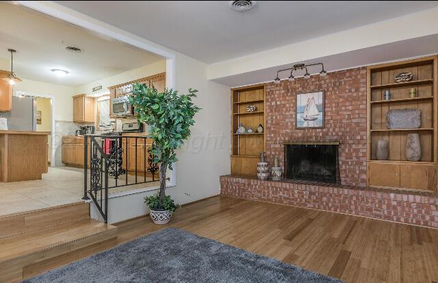 3406 Patterson Dr, Amarillo, TX 79109 - living room featuring light wood finished floors, a brick fireplace, and built in features
