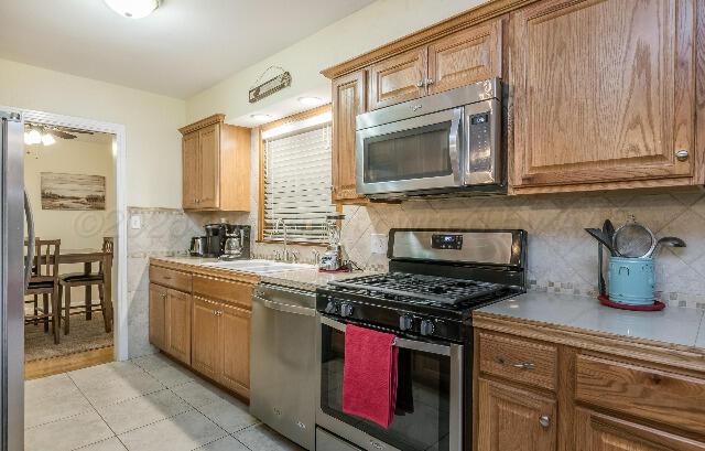 3406 Patterson Dr, Amarillo, TX 79109 - kitchen with stainless steel appliances, a sink, and brown cabinetry