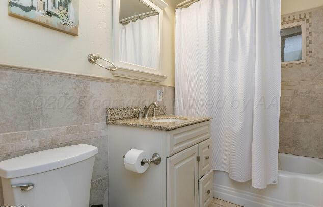 3406 Patterson Dr, Amarillo, TX 79109 - full bath featuring vanity, toilet, shower / tub combo with curtain, and tile walls