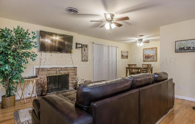 3406 Patterson Dr, Amarillo, TX 79109 - living area featuring a ceiling fan, wood finished floors, baseboards, and a fireplace