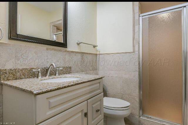 3406 Patterson Dr, Amarillo, TX 79109 - bathroom featuring vanity, a shower stall, tile walls, and toilet
