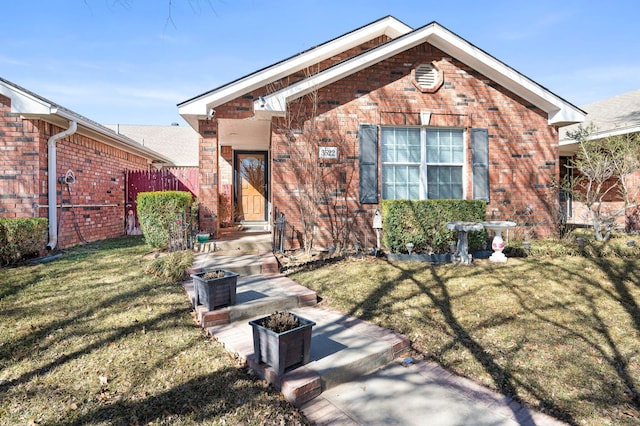 view of front of home with a front yard, brick siding, and fence