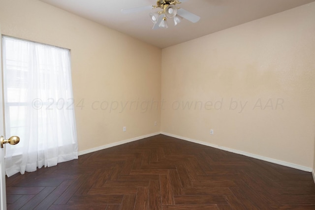 spare room with ceiling fan and dark parquet flooring