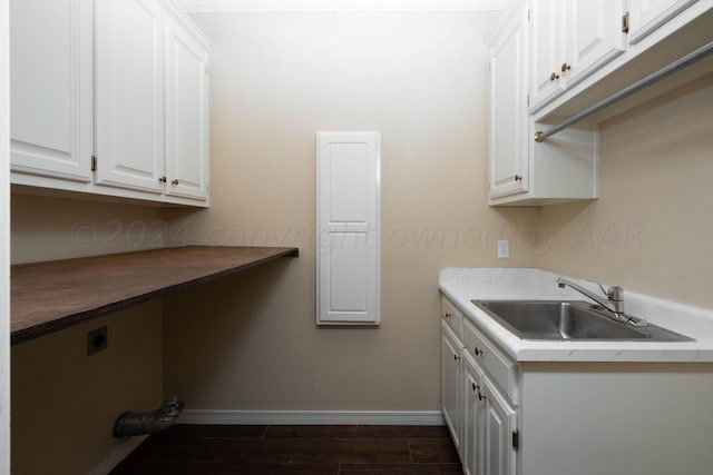 clothes washing area with cabinets, electric dryer hookup, sink, and dark wood-type flooring