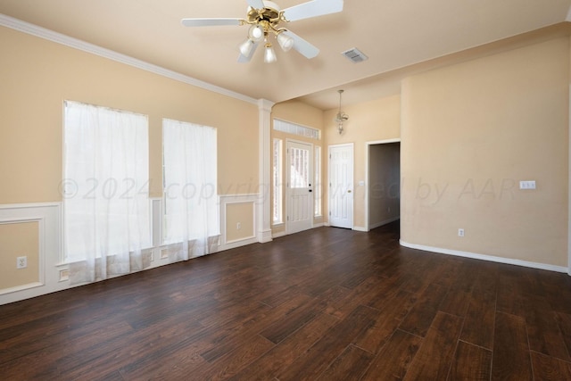 empty room with ceiling fan with notable chandelier, dark wood-type flooring, and crown molding