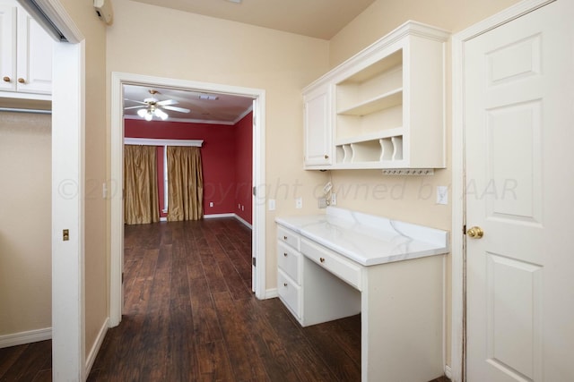 kitchen with white cabinets, ornamental molding, dark hardwood / wood-style floors, ceiling fan, and built in desk