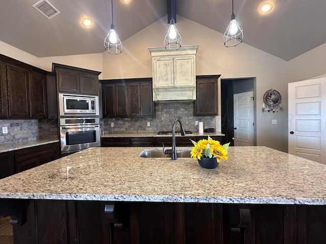 17901 19th St, Amarillo, TX 79124 - kitchen with stainless steel appliances, vaulted ceiling, decorative backsplash, dark brown cabinets, and a large island with sink