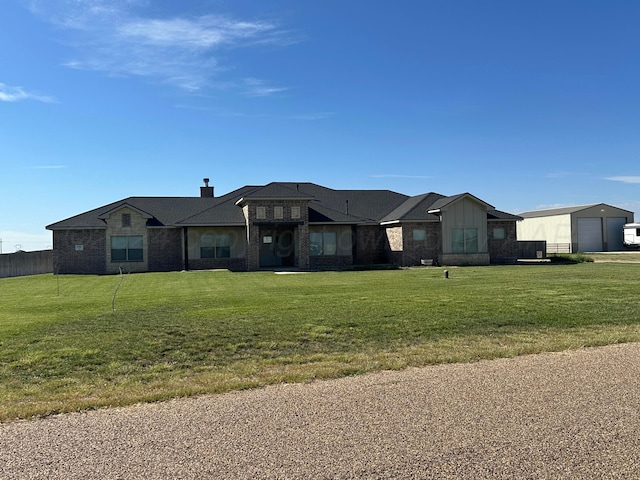 view of front of house featuring a garage, an outdoor structure, and a front lawn