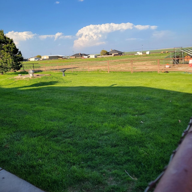 view of yard with fence and a rural view