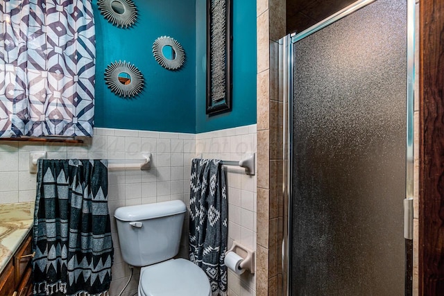 bathroom featuring tile walls, vanity, toilet, and a shower with door