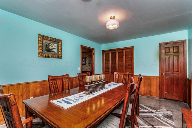 dining room featuring wood walls and concrete flooring