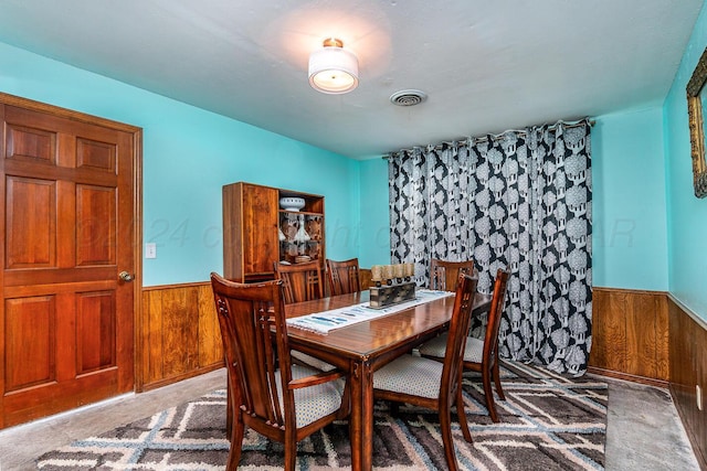 dining room featuring carpet and wood walls