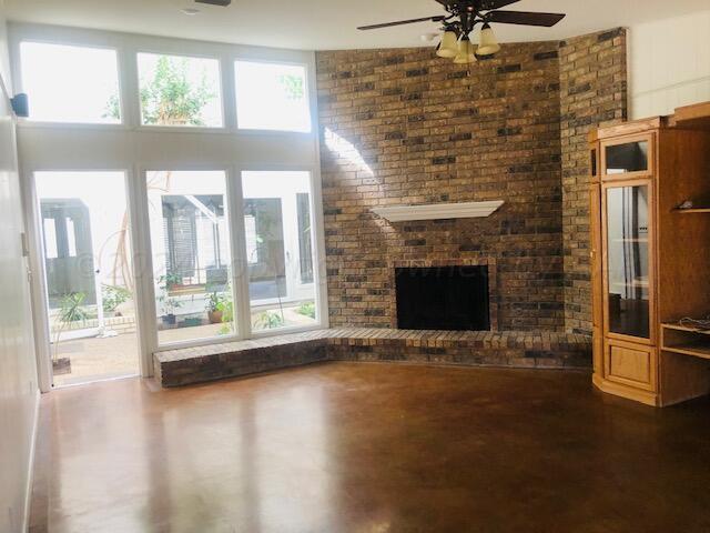 unfurnished living room featuring concrete flooring, ceiling fan, and a fireplace