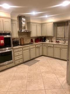 kitchen featuring double oven, black electric stovetop, light tile patterned floors, sink, and wall chimney exhaust hood