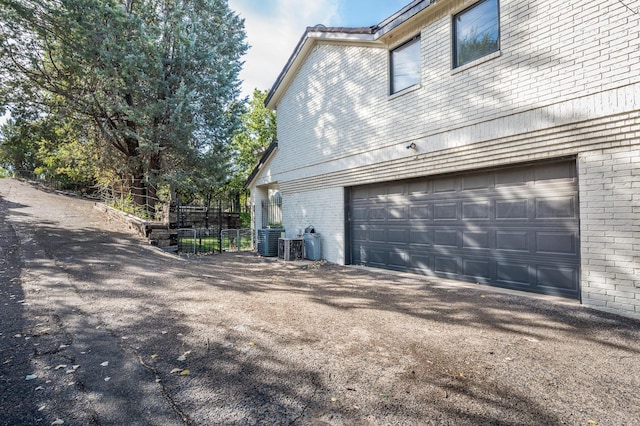 view of home's exterior featuring aphalt driveway, brick siding, and an attached garage