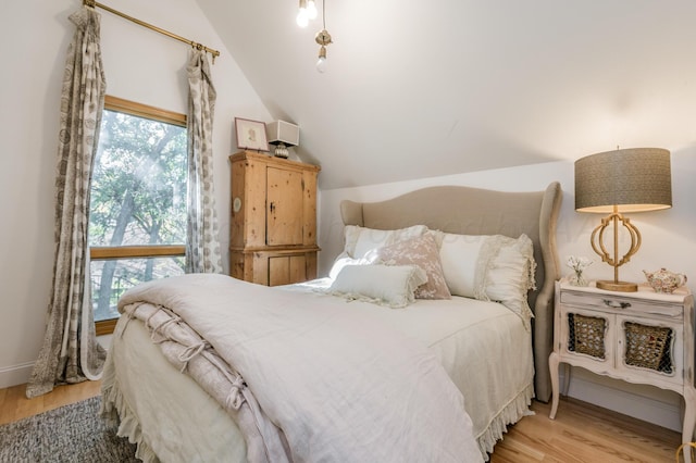 bedroom featuring baseboards, light wood-type flooring, and vaulted ceiling