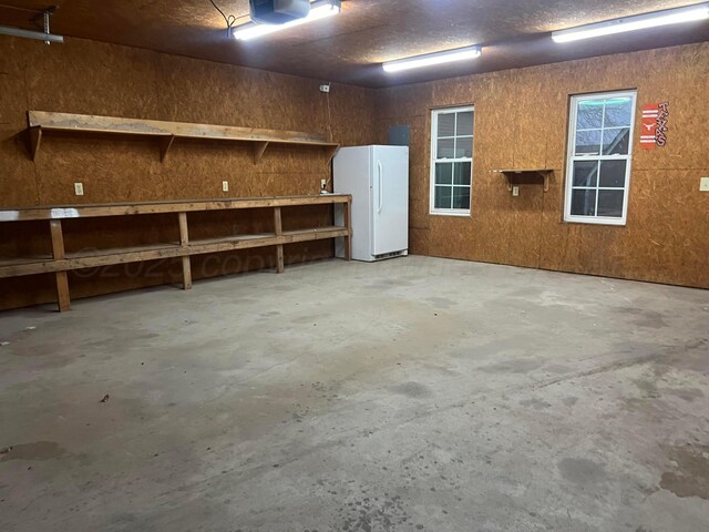 505 S Denton St, Booker, TX 79005 - garage with freestanding refrigerator, a workshop area, and a garage door opener