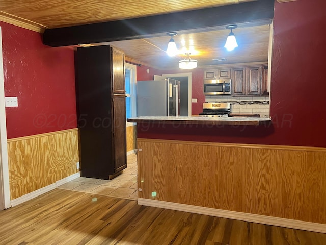 505 S Denton St, Booker, TX 79005 - kitchen with stainless steel appliances, light wood-style flooring, a peninsula, a wainscoted wall, and wood ceiling