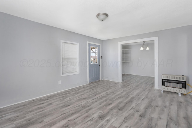 420 N Nelson St, Pampa, TX 79065 - unfurnished living room with baseboards, heating unit, light wood-style flooring, and a notable chandelier