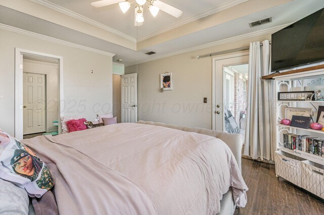 bedroom with dark wood-type flooring, visible vents, a tray ceiling, and ornamental molding