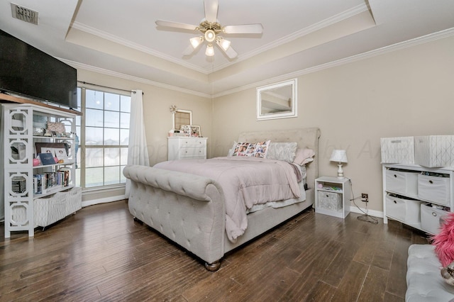 bedroom with a raised ceiling, wood finished floors, and visible vents