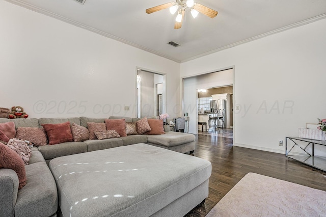 living room featuring dark wood-style flooring, baseboards, crown molding, visible vents, and ceiling fan