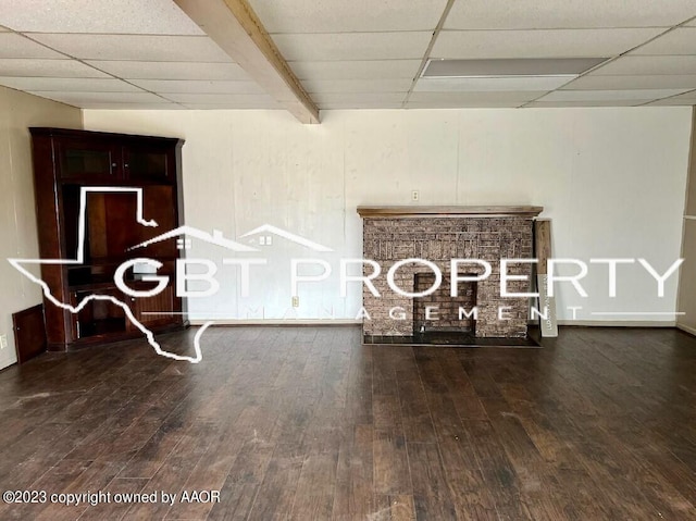 unfurnished living room featuring a drop ceiling and dark hardwood / wood-style flooring