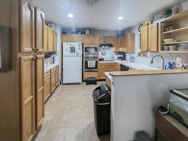 kitchen featuring wall oven, tasteful backsplash, stainless steel microwave, freestanding refrigerator, and light countertops