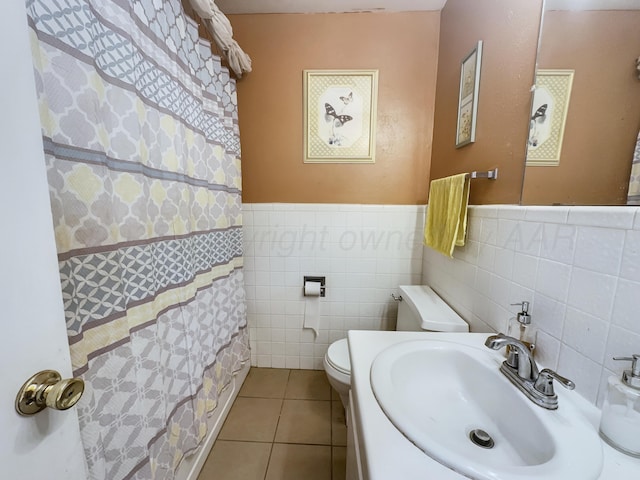 bathroom with wainscoting, toilet, tile patterned floors, curtained shower, and a sink