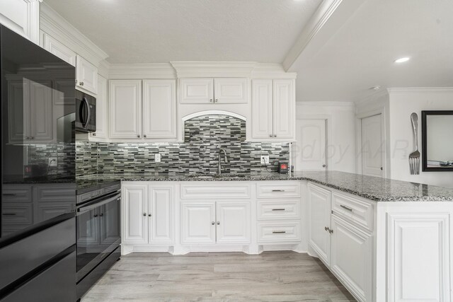 4102 SE 12th Ave, Amarillo, TX 79104 - kitchen with dark stone counters, a peninsula, white cabinets, tasteful backsplash, and recessed lighting