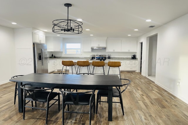 dining room with light hardwood / wood-style flooring, a notable chandelier, and sink