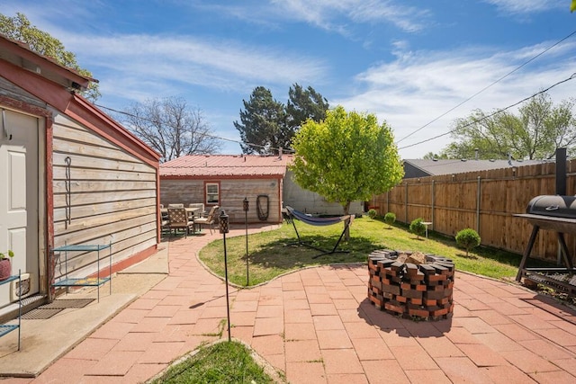 view of patio / terrace with area for grilling, a fenced backyard, a fire pit, and an outbuilding