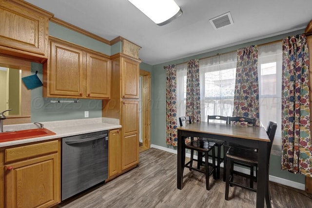 kitchen featuring stainless steel dishwasher, a sink, baseboards, visible vents, and light countertops