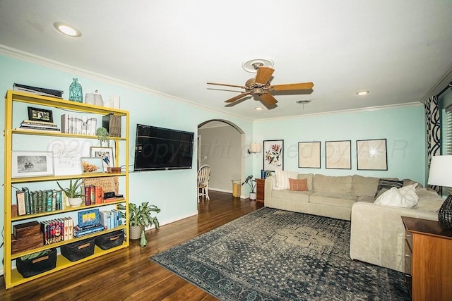 living area featuring ornamental molding, wood finished floors, baseboards, arched walkways, and a ceiling fan