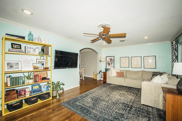 living room featuring ceiling fan, arched walkways, wood finished floors, baseboards, and ornamental molding